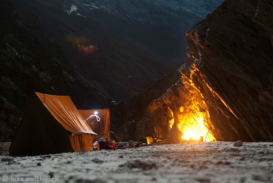 Zanskaris warm up next to a fire under a full moon on the banks of the frozen Zanskar river. Chadar, India